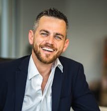 Business professional in suit smiling confidently in a modern office environment.